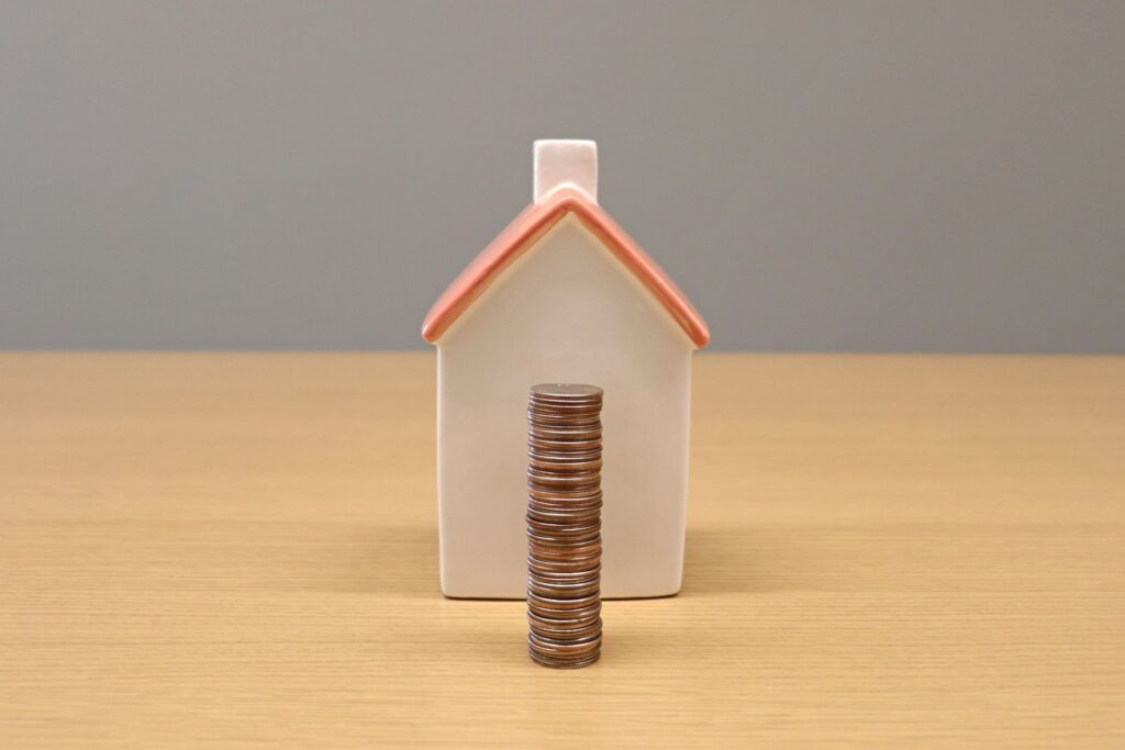 Small house model with a stack of coins, representing roof financing and home improvement savings