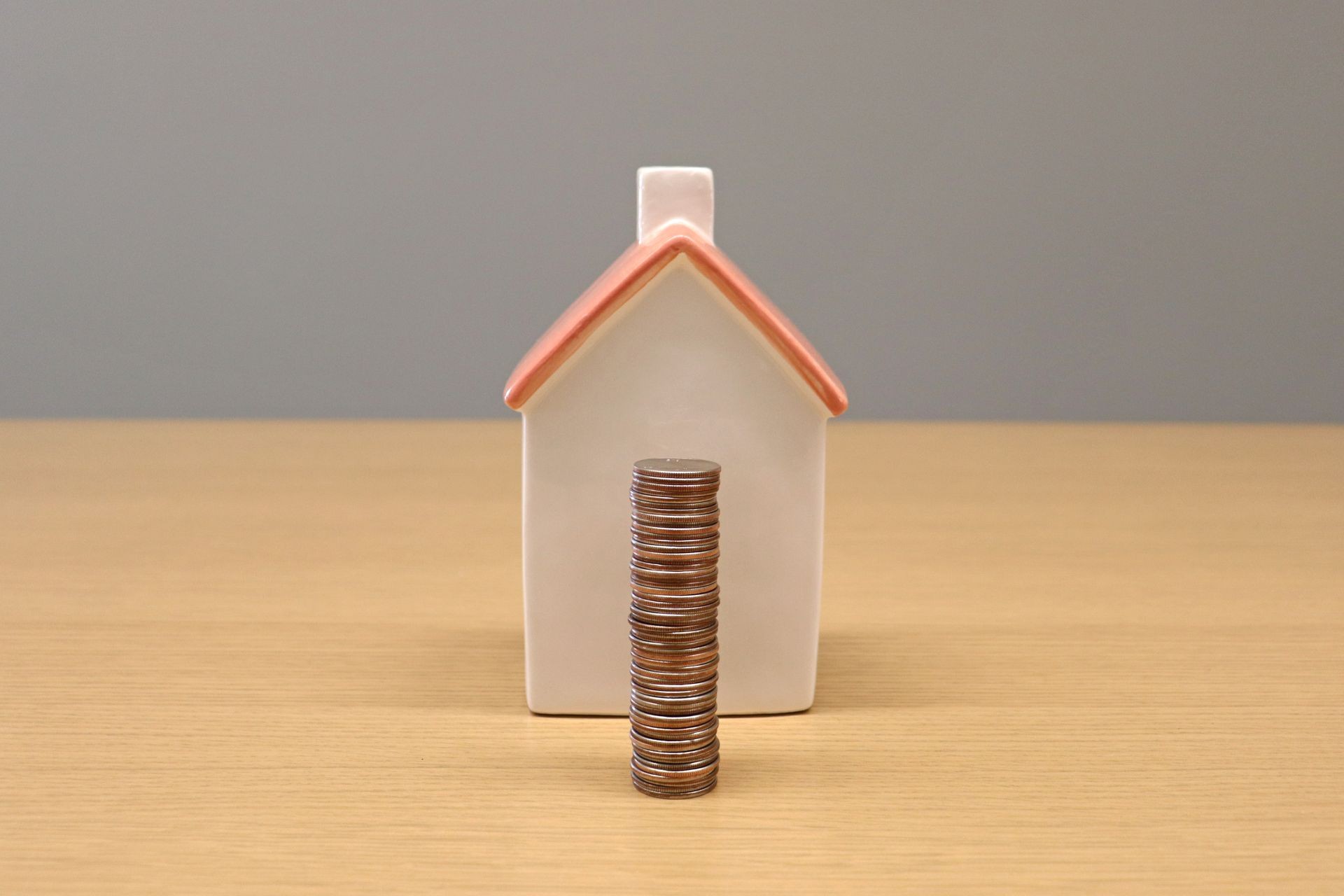 Small house model with a stack of coins, representing roof financing and home improvement savings